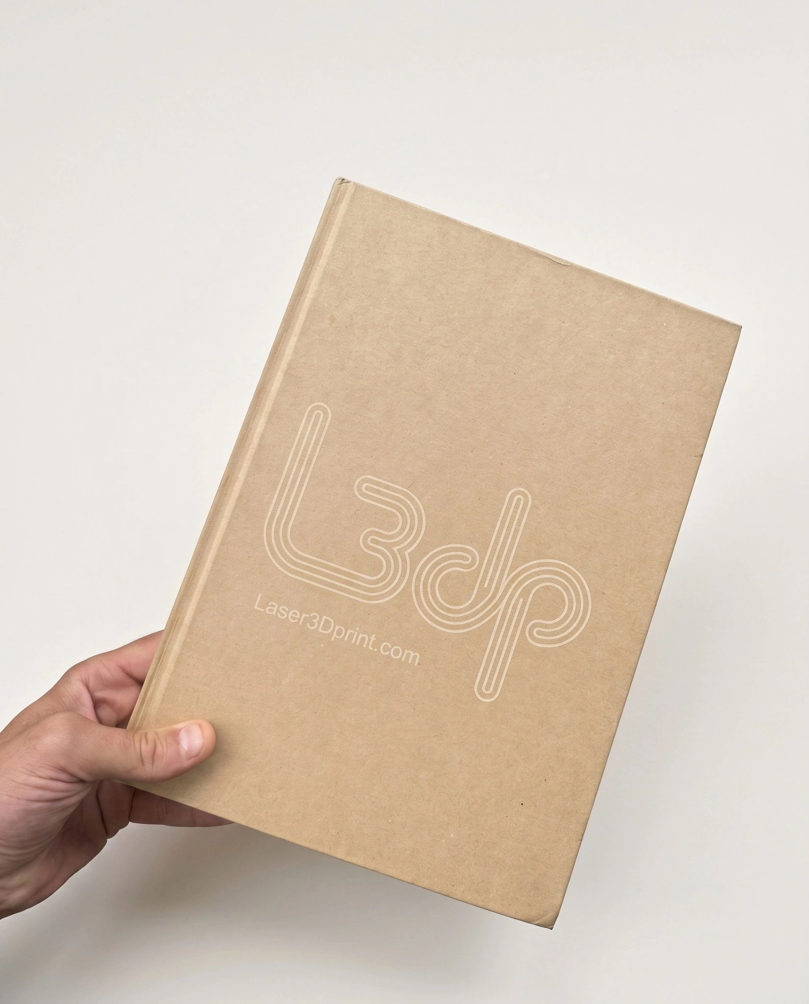 Cahier à couverture kraft gravé au laser avec logo L3dp et inscription Laser3Dprint.com, tenu à la main.