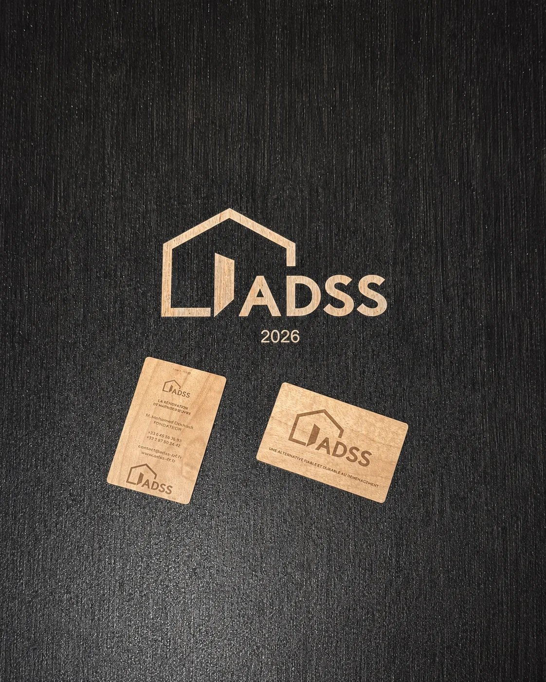 Décapage laser d’une peinture noire sur bois avec logo ADSS et cartes de visite en bois gravées.