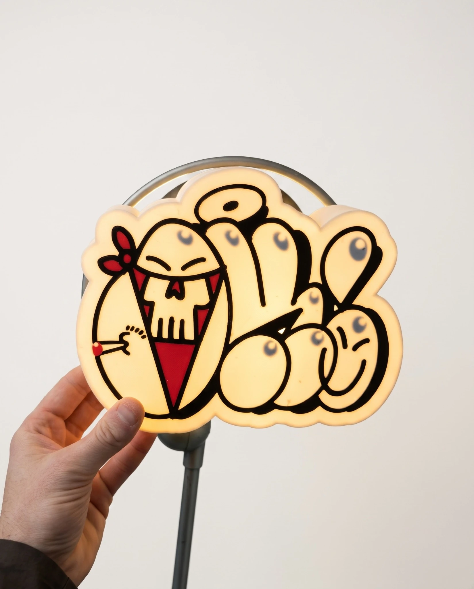 Lightbox multicolore imprimée en 3D, éclairée, avec motif graphique personnalisé, tenue à la main sur fond neutre.